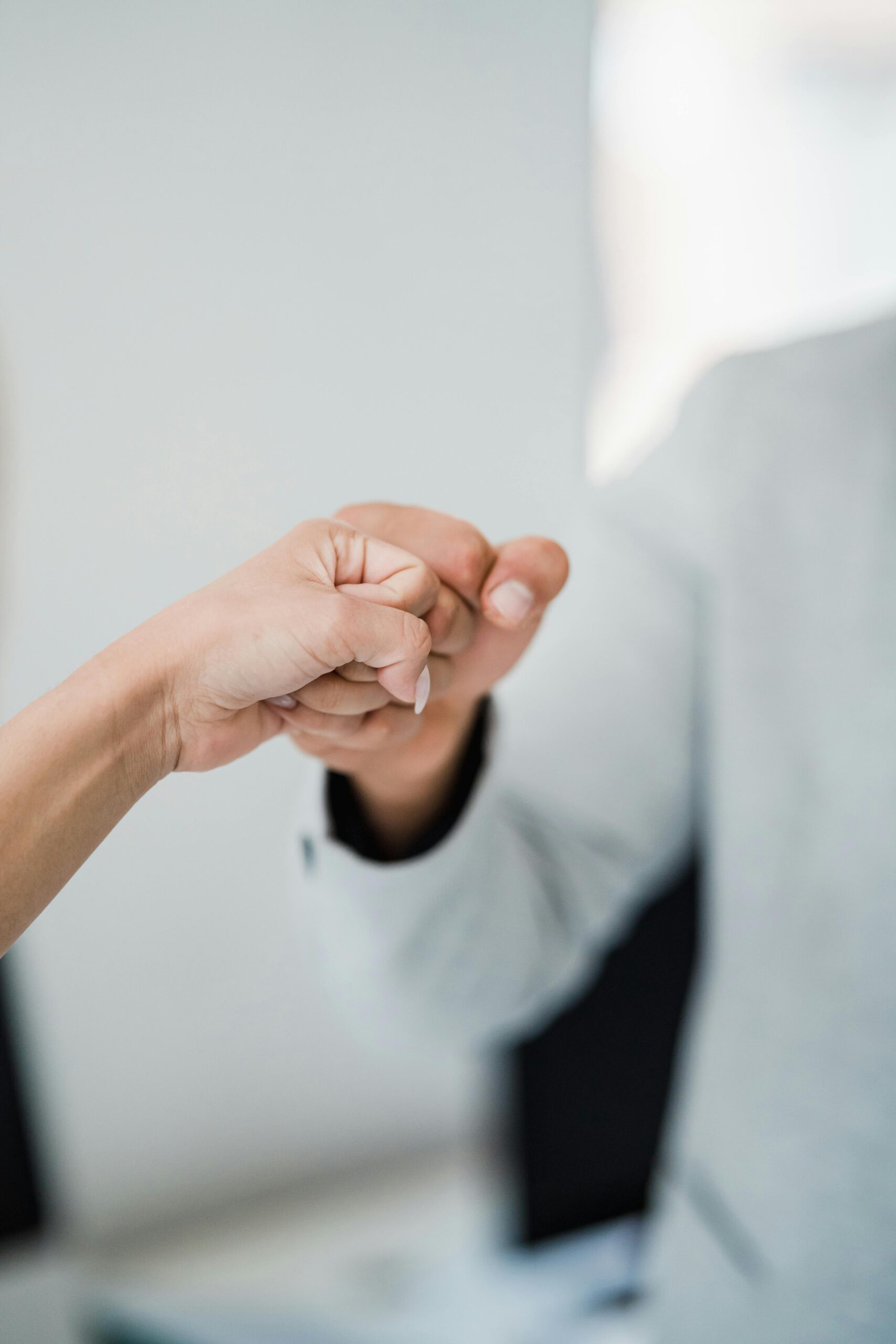 Home Close-up of two professionals bumping fists, symbolizing teamwork and respect in a modern office.
